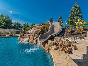 freeform st. louis custom designed concrete pool with fiberglass water slide and boulder waterfall water feature