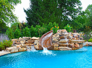 freeform st. louis custom designed concrete pool with concrete water slide and large boulder waterfall water feature