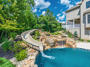 freeform st. louis custom designed concrete pool with fiberglass water slide and boulder waterfall water feature