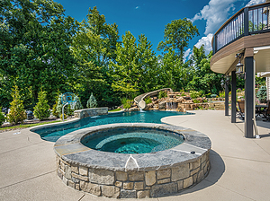 st. louis custom designed freeform concrete pool, raised concrete spa with stone veneer and flagstone cap