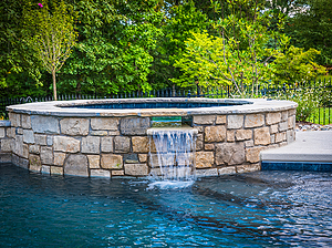 st. louis custom designed concrete pool, raised concrete spa with spillway, stone veneer and flagstone cap