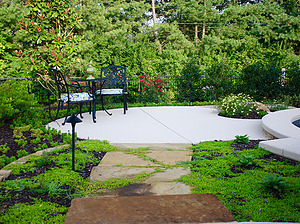 flagstone pathway leading to round concrete patio with small seating area