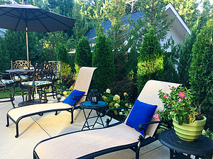 Concrete patio with table and chairs, beige and blue lounge chairs