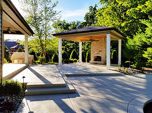 Concrete patio with gazebo structure and stone fireplace