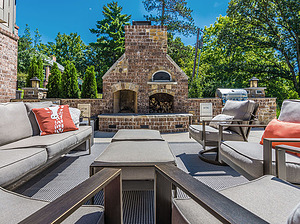 concrete patio with seating area, beige outdoor furniture, brick fireplace with pizza oven