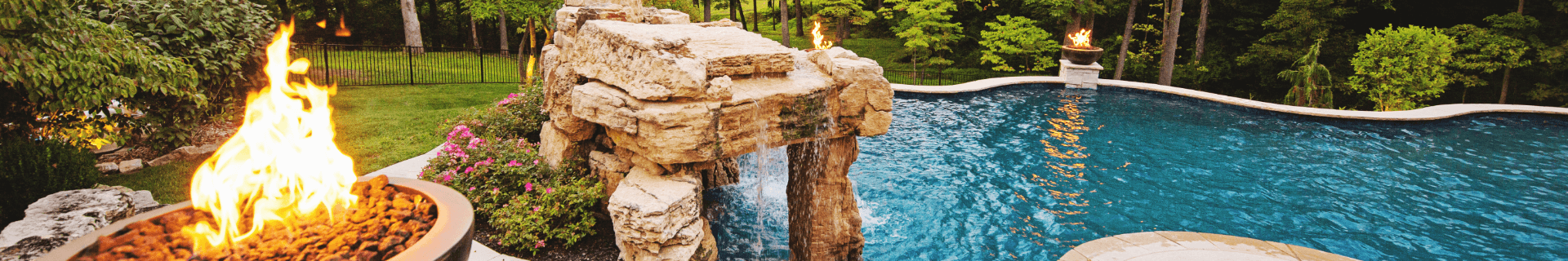 stone waterfall and firepit features at one end of an ornately landscaped pool